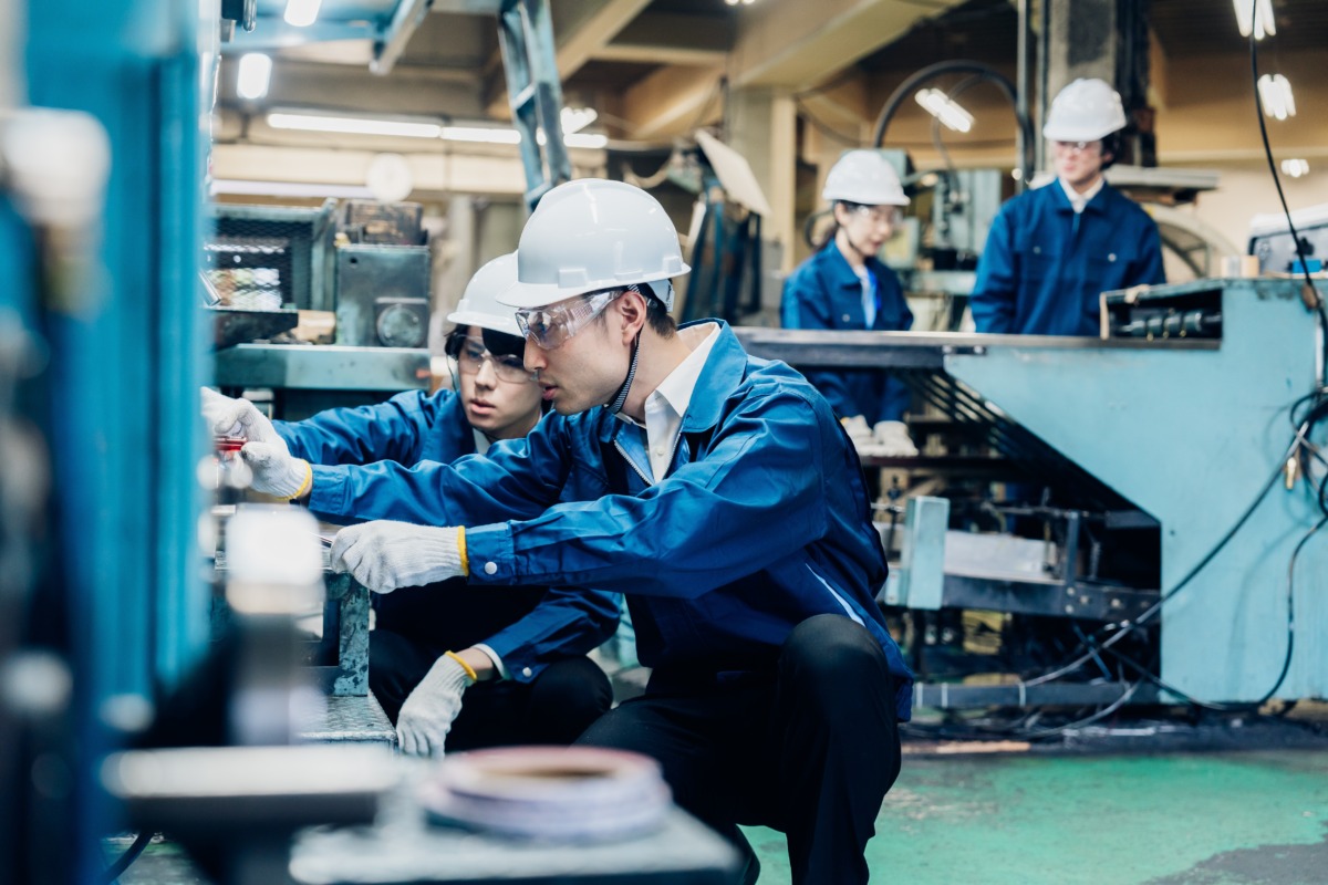 Japanese manufacturing workers inspecting factory machinery as part of industrial operations, symbolizing overseas expansion planning.