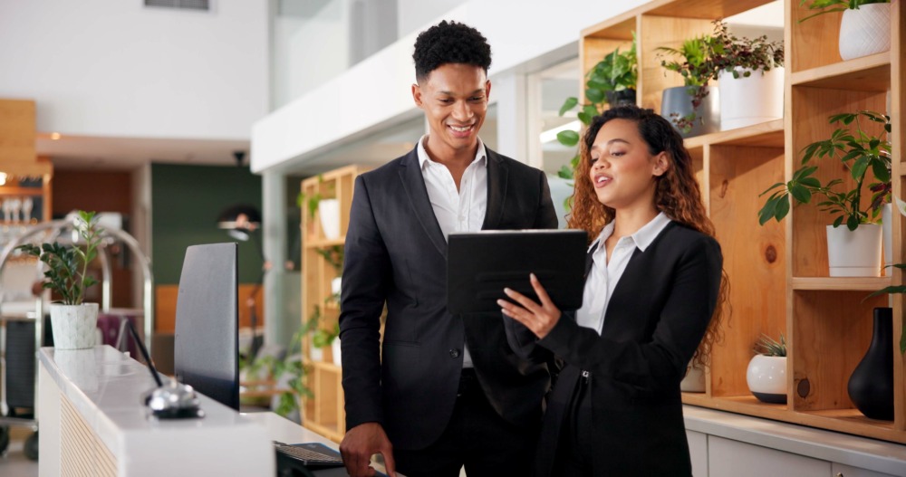 Hospitality professionals in a modern reception area reviewing information on a tablet, symbolizing strategies for service industry businesses to succeed in international expansion and avoid failures