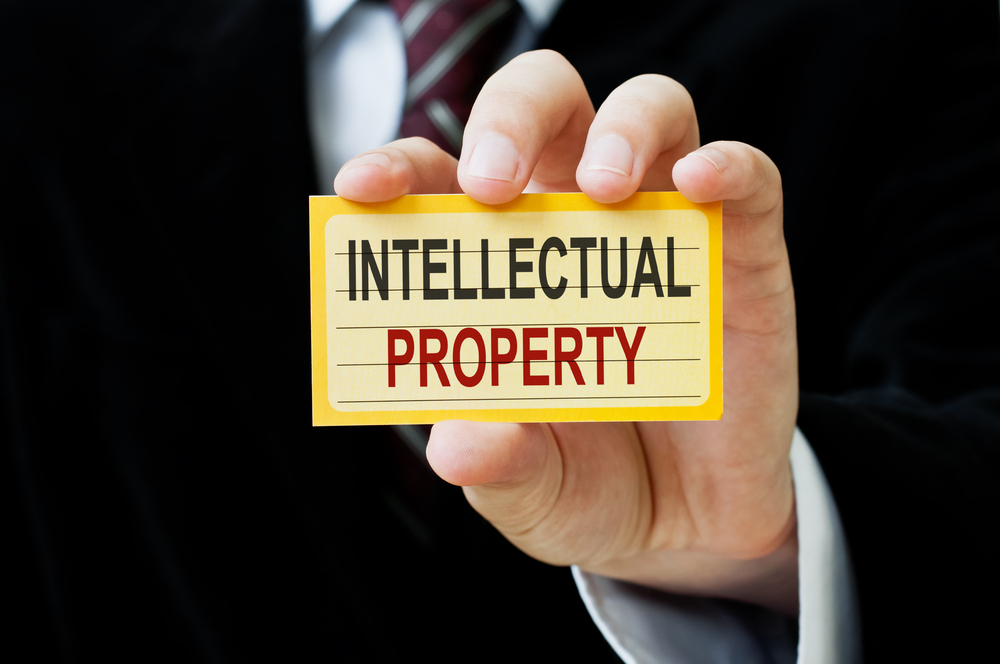 Businessman holding a card that says Intellectual Property, symbolizing the importance of IP protection in global business.